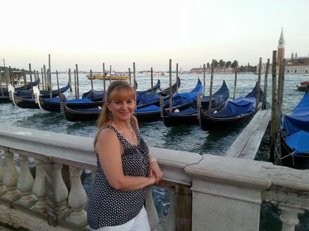 Yenesis standing in front of small boats off a dock in Italy